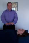 Reiki practitioner holds his hands over the client's heart chakra, channeling energy.